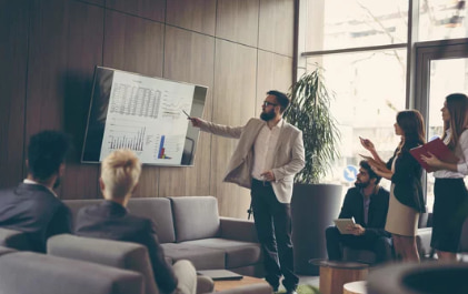 Business professional presenting data analysis to a group in a modern office.